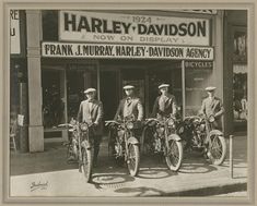 three men are standing in front of a bicycle shop with their bikes parked outside the store