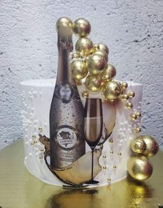 a bottle of champagne and some gold balls on a table next to a white cake