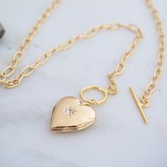 "Adorable gold heart locket necklace features a heart shaped locket that opens up to hold a secret message or small photos of your loved ones.  The pendant is suspended on a paperclip chain finished with a unique toggle clasp. It is a perfect gift for your girlfriend, mother, or loved one for Valentine's Day, Mother's Day, or as birthday gift. DETAILS: ------------- Adorable heart shaped photo locket pendant with a sparkly cubic zirconia center stone. Opens to a compartment to put in photograph Locket Necklace Heart, Gold Heart Locket Necklace, Locket Jewelry, Message Necklace, Gold Heart Locket, Heart Photo, San Ramon, Jewelry Heart, Heart Locket Necklace