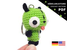 a crocheted keychain with a green creature on it's face