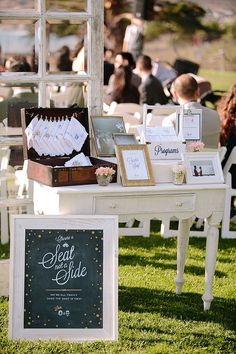 a table with pictures and other items on it in front of an open window at a wedding