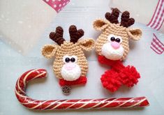 two crocheted reindeers are sitting next to a candy cane