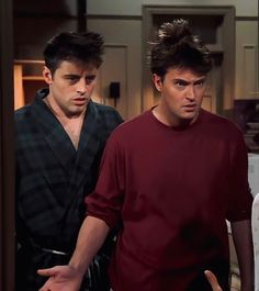 two young men standing next to each other in front of a kitchen counter and refrigerator