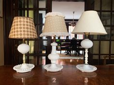 three lamps sitting on top of a wooden table next to a lamp shade and numbers