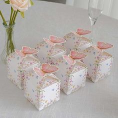 there are six small boxes on the table next to a vase with flowers in it