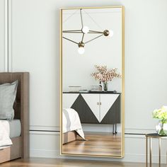 a large mirror sitting on top of a wooden floor next to a bed and nightstand