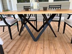 a wooden table sitting on top of a hard wood floored porch next to a window