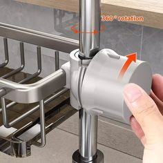 a hand is holding the handle on a stainless steel sink faucet with an orange arrow pointing to it