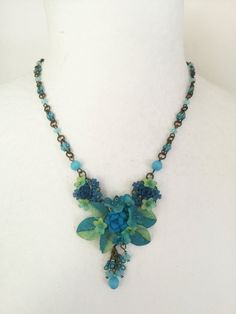 We call this color Azure with deep shades of teal, shaded with soft aqua mixed together. This is a smaller necklace beaded with glass beads and hand painted resin flowers. The central motif measures 1.5 inches across with a deep turquoise blue rose and is flanked on either side with drops that are 1.5 inches long. The chain is also handbeaded. This piece is great for someone who likes a smaller more delicate necklace. Lovely color for the beach. There are two matching earrings available for this Deep Turquoise, Painted Resin, Small Necklace, Shades Of Teal, Blue Pendant, Necklace Beaded, Azure Blue, Floral Necklace, Resin Flowers