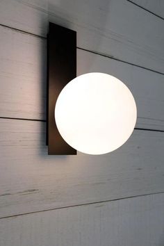 a light that is on the side of a wall next to a white wall with wood planks