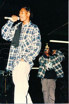 two young men standing on stage with microphones in their hands and one holding a bottle