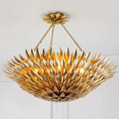 a chandelier hanging from the ceiling with gold leaves on it's petals