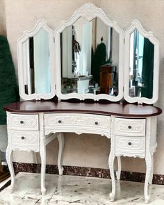 an antique white dressing table with mirror and stool on marble floor in front of wall