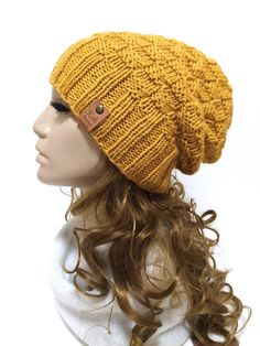 a mannequin head wearing a yellow knitted beanie hat with leather button