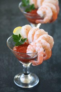 two martini glasses filled with shrimp and garnish