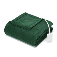 a green blanket with an electric outlet plugged into it