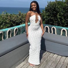 a woman in a white dress standing on a deck