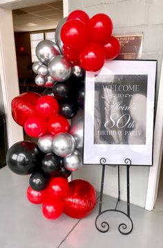 a welcome sign and balloon arch for a 50th birthday party with red, black and silver balloons