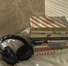 a stack of books and headphones sitting on top of a bed next to each other