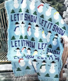 a knitted blanket that says let it snow, let it snow on the bench