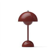 a red table lamp sitting on top of a white floor