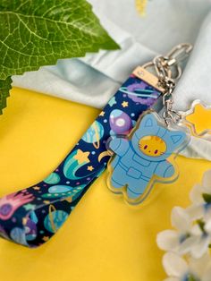 a keychain with a cartoon character on it sitting next to flowers and leaves