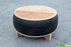 a wooden stool made out of an old tire is sitting on the concrete and looks like it has been turned into a coffee table