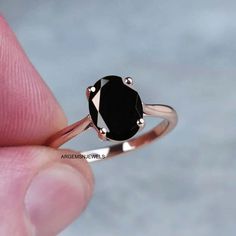 a woman's hand holding a black diamond ring