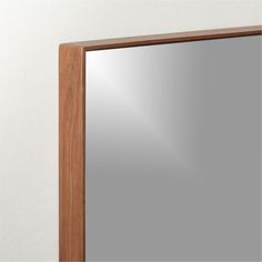 a mirror mounted to the side of a white wall next to a wooden frame and wood trim