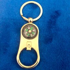 a golden metal keychain with a green compass on it's side and a blue background