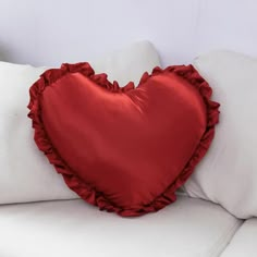 a red heart shaped pillow sitting on top of a white couch