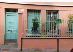 a pink building with green shutters and potted plants on the balconies