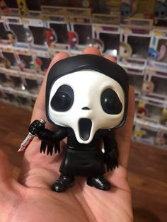 a hand holding a toy with a black and white skeleton face on it's head