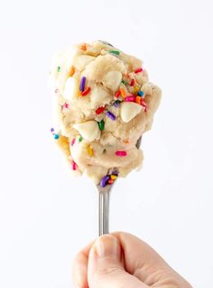 a hand holding a scoop of ice cream with sprinkles