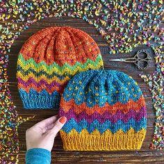 two knitted beanies sitting next to each other on top of a wooden table