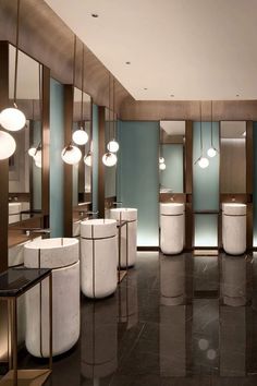 a large bathroom with marble floors and lights hanging from the ceiling, along with round sinks