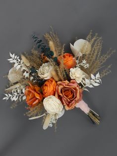 an arrangement of flowers and feathers on a gray background with white, orange, and gold accents