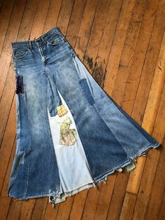 three pairs of jeans sitting on top of a wooden floor