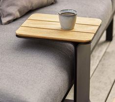 a cup of coffee sitting on top of a wooden table next to a gray couch