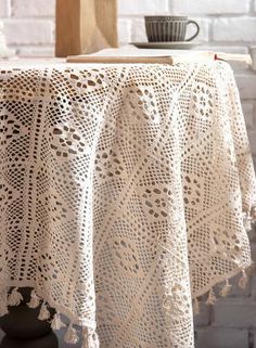 a table topped with a white crocheted doily next to a cup and saucer