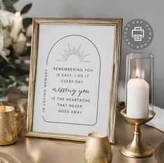 a white and gold framed print on a table next to some candles, flowers and other items