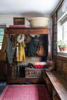 a wooden bench sitting next to a shelf filled with hats and coats on top of it