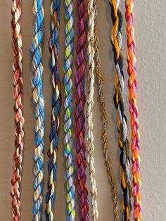 multicolored braids are hanging on the wall next to each other in rows