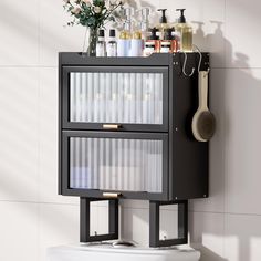 a bathroom with a white toilet and a black cabinet on the wall next to it