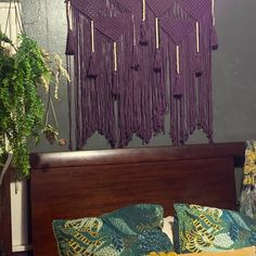 a bed topped with purple crocheted pillows next to a wooden headboard