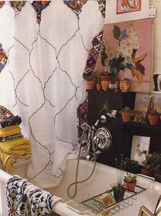 a bath tub sitting next to a window covered in curtains and potted plantes