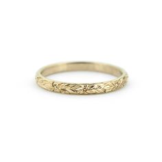 a gold wedding band with leaves on it