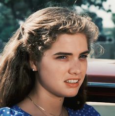 a close up of a person in a car wearing a necklace and smiling at the camera