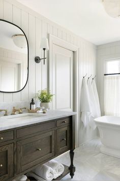 a bathroom with a sink, mirror and bathtub next to a window in it