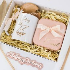 a pink and white gift box containing two coffee mugs with spoons in it